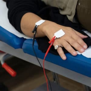 Una persona distesa su un lettino, in uno studio medico, viene sottoposta a un esame di bioimpedenziometria