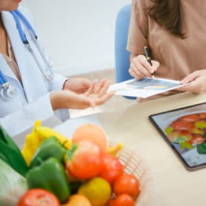 Una nutrizionista parla insieme a una giovane paziente, mostrandole delle tabelle nutrizionali.